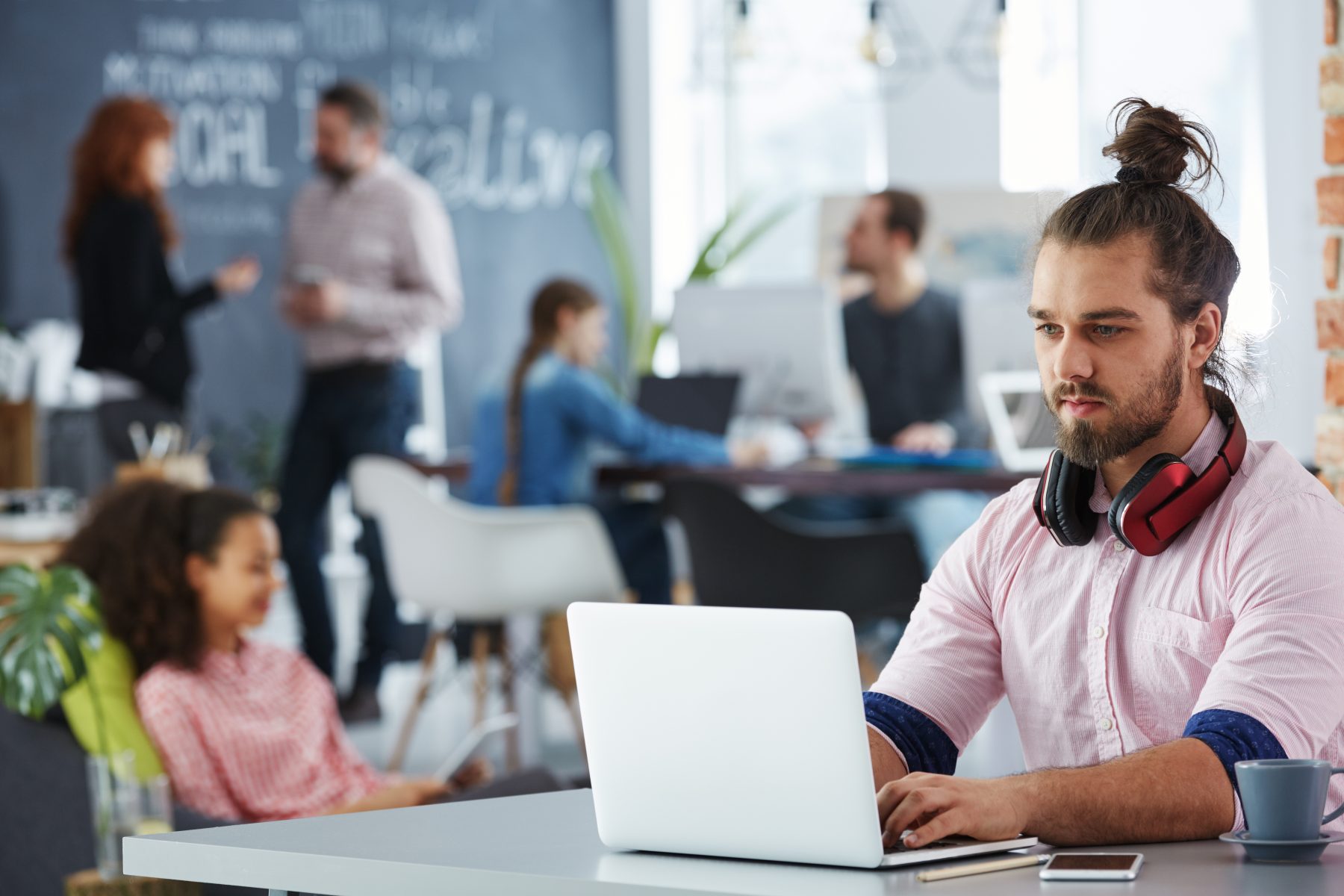 Young confident man working on startup DAM using laptop in co-creative studio