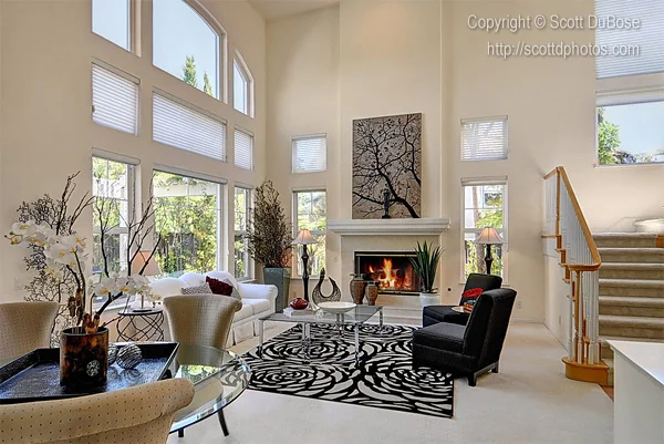 Bright two-story living room with fireplace, black-and-white patterned area rug, staircase, and tall windows photographed by Scott DuBose