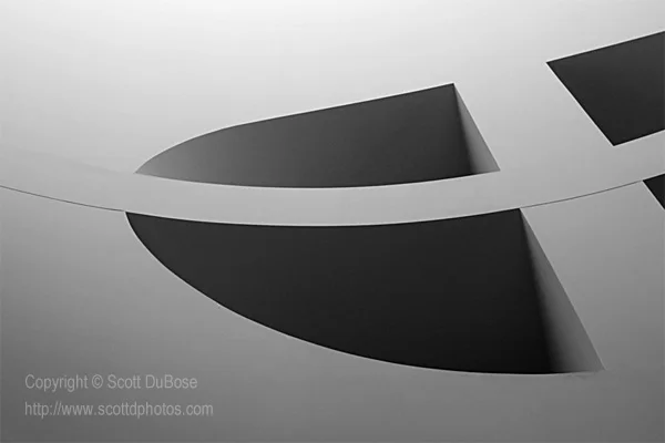 Abstract close-up of curved concrete architectural surfaces with dramatic contrasting shadows and geometric forms photographed by Scott DuBose